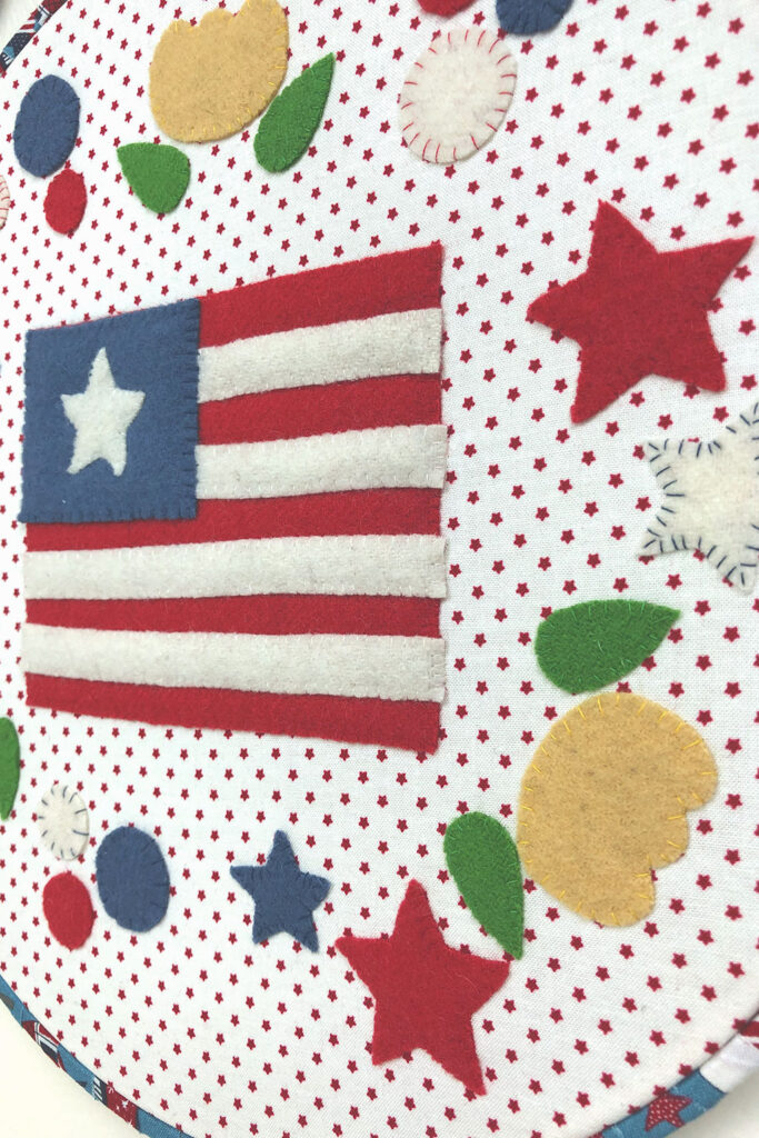 Flag, stars and flowers adorn this patriotic themed wool applique hoop.