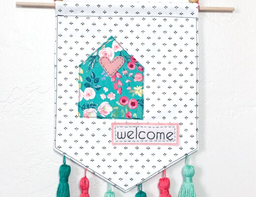 Welcome Wall Banner DIY by top US sewing blog Ameroonie Designs: image shows the finished welcome banner with floral cottage and embellishments