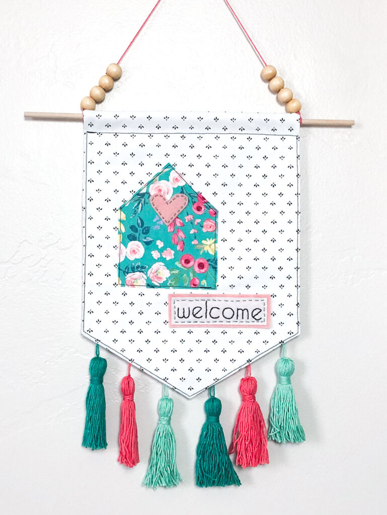 Welcome Wall Banner DIY featured by Top US sewing blog Ameroonie Designs: image of floral cottage on black and white banner with tassels