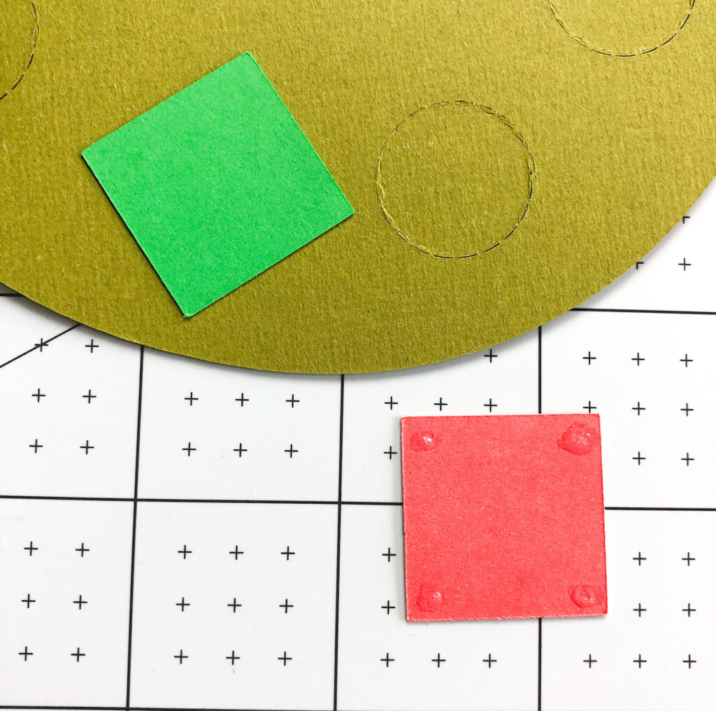 Personalized Christmas Countdown featured by top US craft blog Ameroonie Designs: Image of gluing colored squares to back of perforated circle