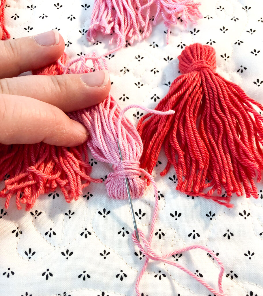 Tassel Pillow DIY featured by top US sewing blog Ameroonie Designs: image of securing the threads that creates the head and neck of tassel.