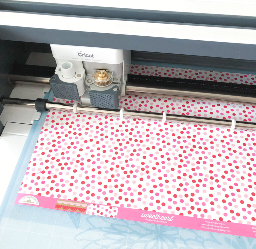 DIY Valentine Countdown Banner with the Cricut Maker featured by top US craft blog Ameroonie Designs: image of Cricut Maker perforating blade cutting hearts for banner.