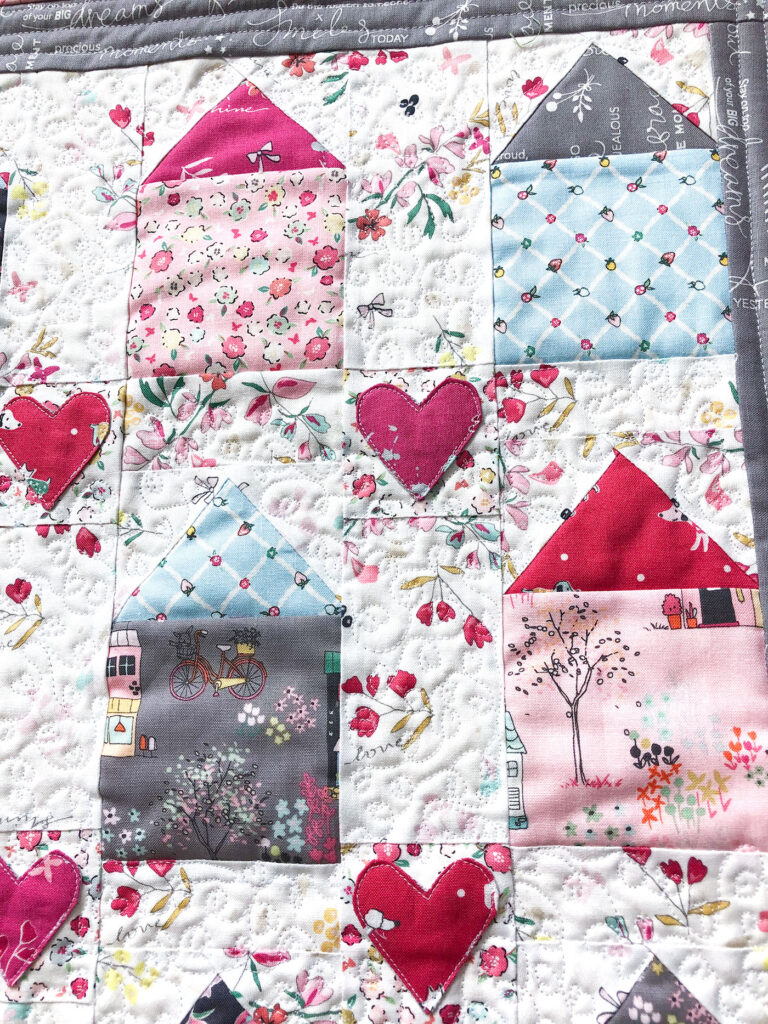 Community Love mini quilt by Top US Sewing Blog Ameroonie Designs. Image of: close up of quilt to show free motion quilting using small hearts.