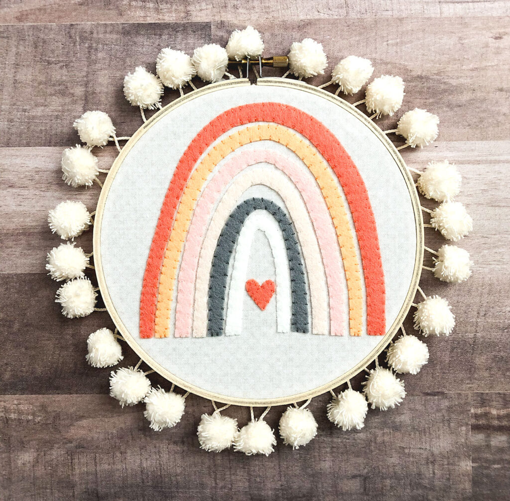 Mini Rainbow Applique Pattern by top US sewing blog Ameroonie Designs image of: wool felt rainbow in soft pastel colors in embroidery hoop.