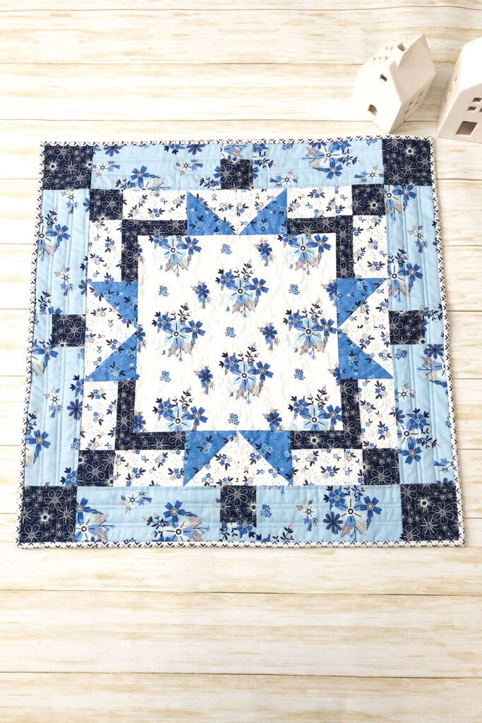 Easy table topper quilt by Top US sewing blog Ameroonie Designs. Image of: table topper with ceramic houses.