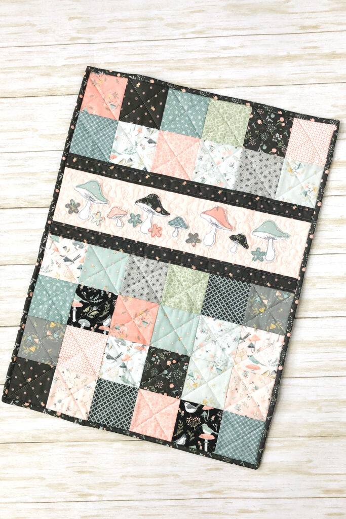 Patchwork doll quilt by top US sewing blog Ameroonie Designs. Image of finished patchwork doll quilt.