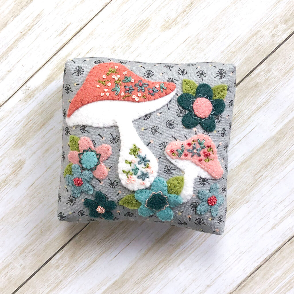 Patchwork doll quilt by top US sewing blog Ameroonie Designs. Image of applique pillow.