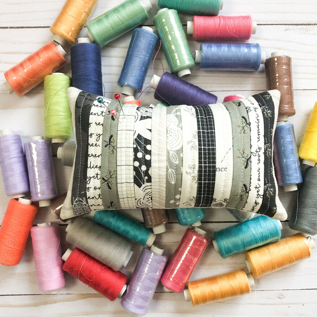 Scraptastic and simple Strip Pincushion by top US sewing blog Ameroonie Designs. Image of: neutral pincushion in colorful thread.