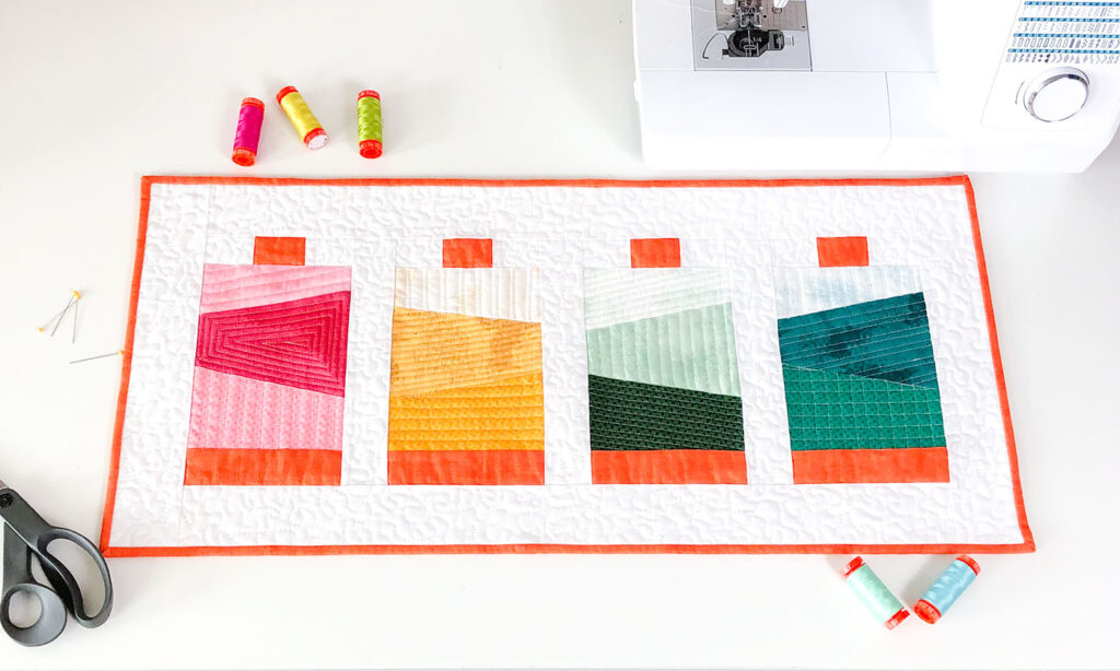 Thread spools create a sewing themed mini quilt.