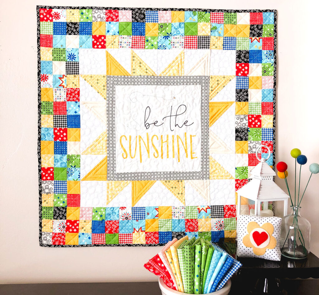 Sew a stunning mini quilt with a fabric panel by top US sewing blog Ameroonie Designs. Image of Be the Sunshine mini quilt.