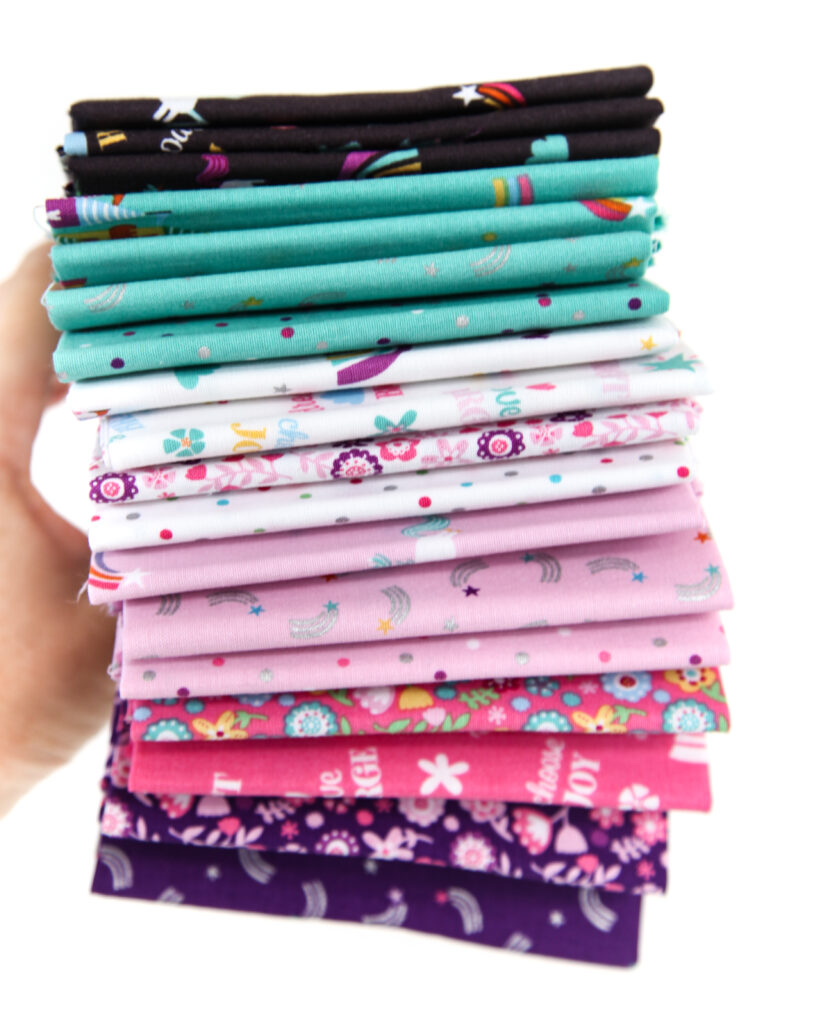 Sew an adorable backpack by top US sewing blog Ameroonie Designs. Image of fat quarters of Unicorn Kingdom fabric prints.