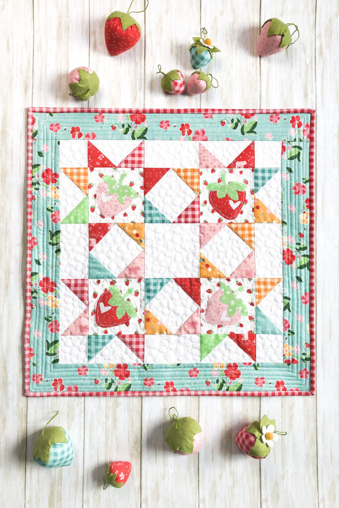 Strawberry Springtime mini quilt free pattern by top US sewing blog Ameroonie Designs. Image of strawberry springtime mini quilt with stuffed strawberries.