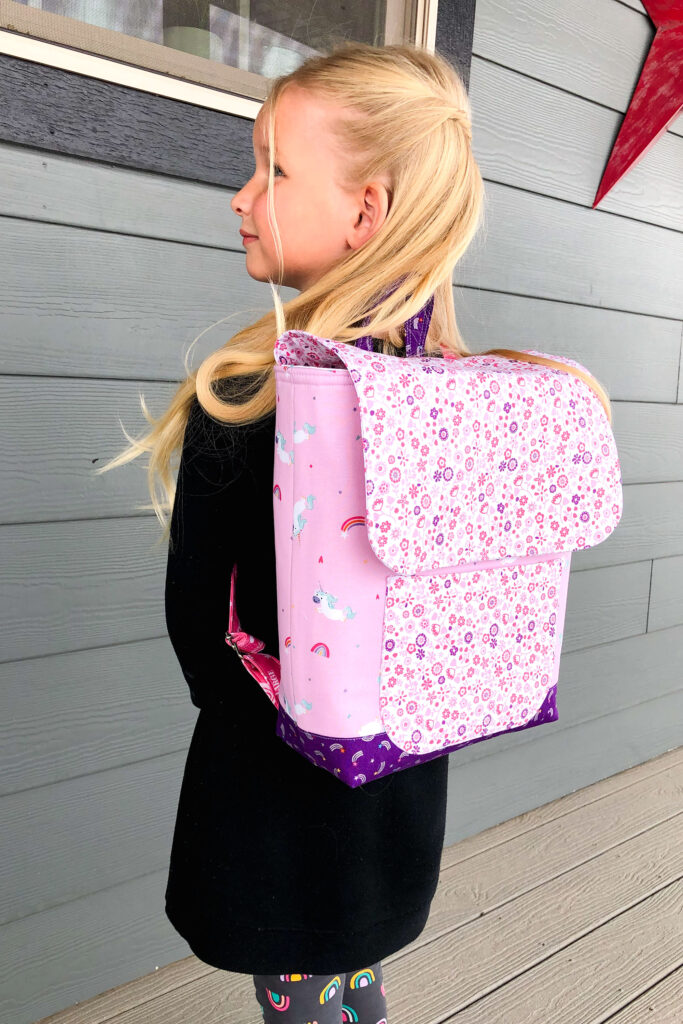 Sew an adorable backpack by top US sewing blog Ameroonie Designs. Image of girl wearing pink backpack.