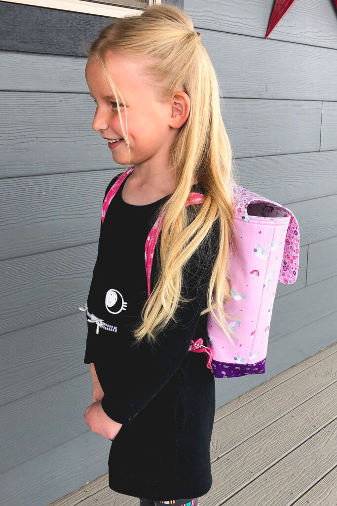 Sew an adorable backpack by top US sewing blog Ameroonie Designs. Image of girl wearing unicorn backpack.