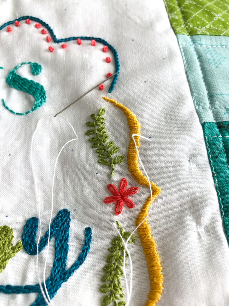 Turn your embroidery into a stunning mini quilt by Top US sewing blog Ameroonie Designs. Image of hand quilting stitches to tack down embroidery.