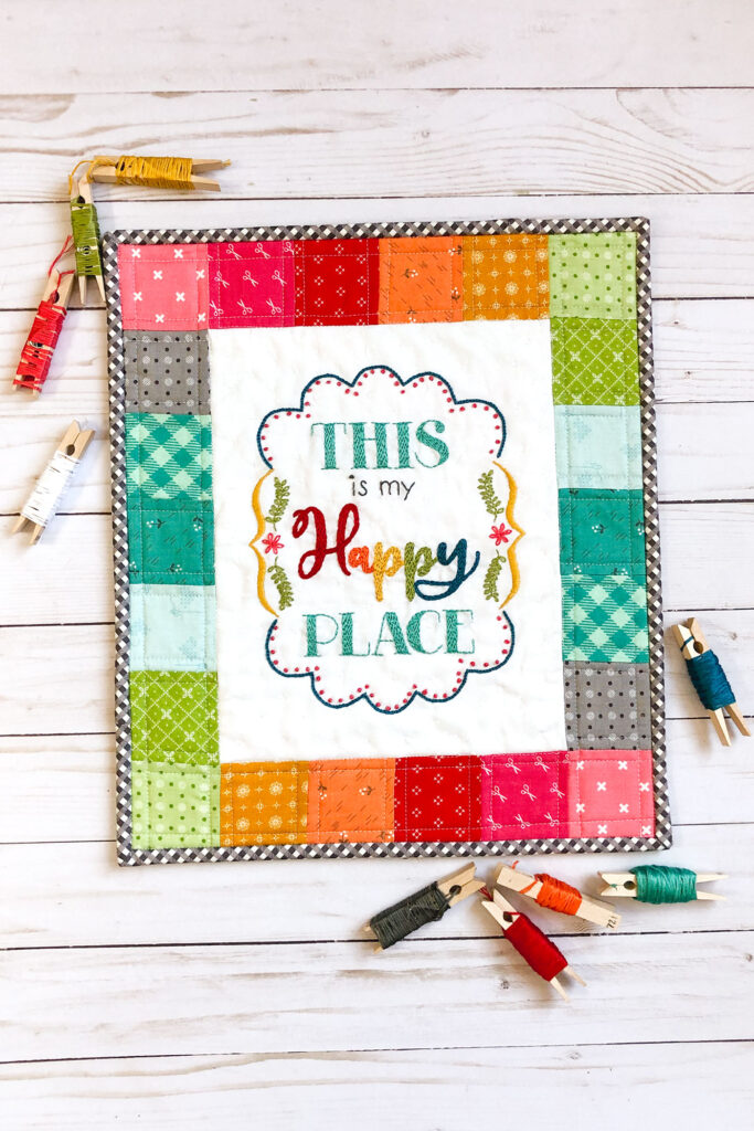 Turn your embroidery into a stunning mini quilt by Top US sewing blog Ameroonie Designs. Image of Mini quilt with embroidery and clothespins wrapped with embroidery floss.