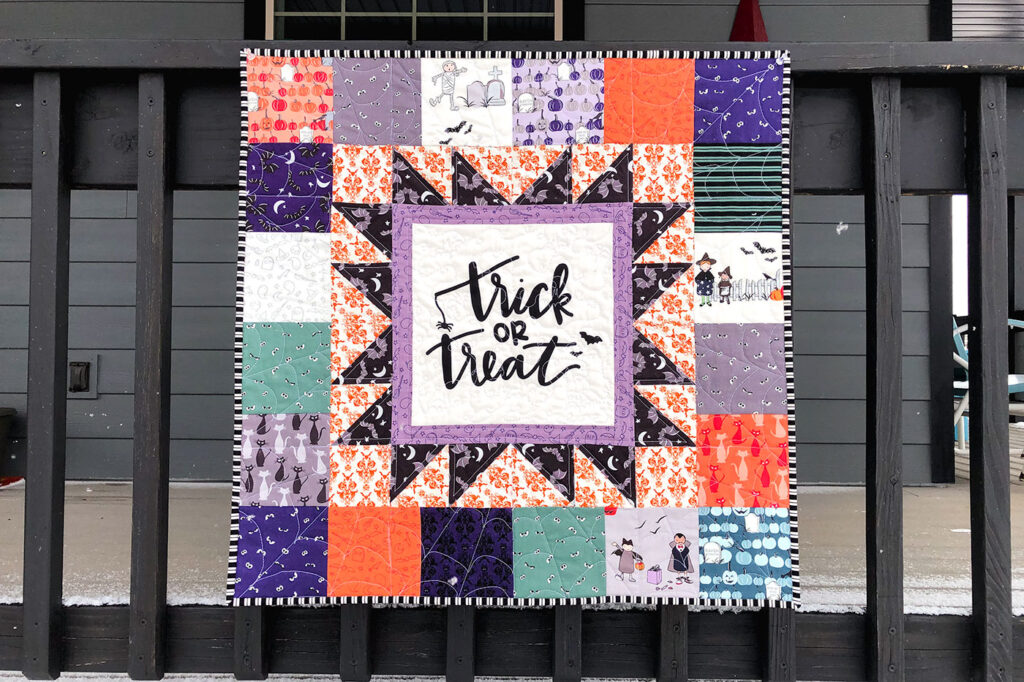 Turn a fabric panel into a stunning mini quilt from Top US sewing blog Ameroonie Designs. Image of mini quilt featuring Spooky Hollow fabric on black railing.