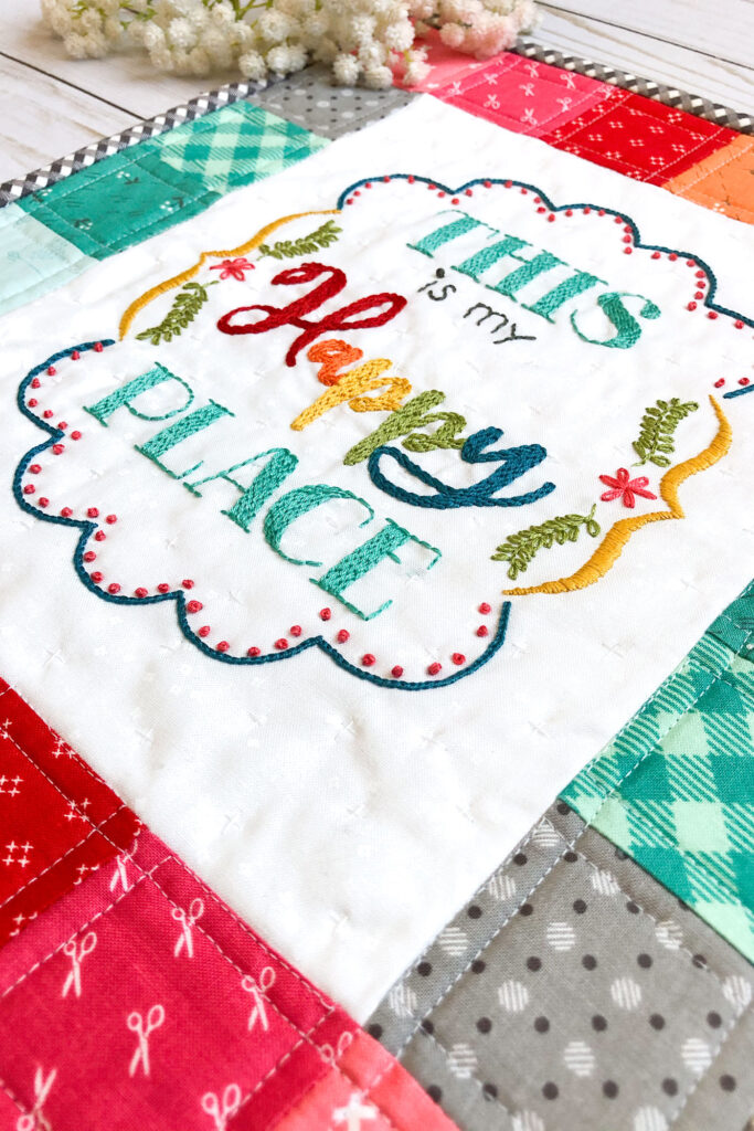 Learn how to stitch a layered back stitch. Image of mini quilt with embroidered sentiment saying, "This is my happy place."