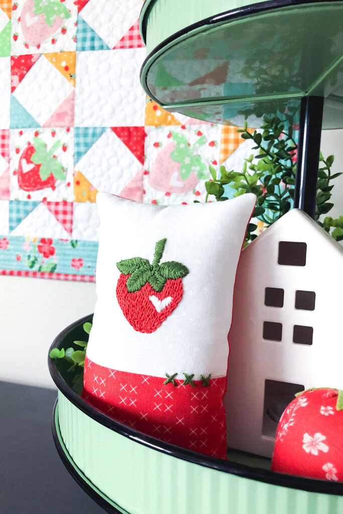 How to sew an easy embroidered strawberry mini pillow with top US sewing blog Ameroonie Designs. Image of mini pillow in tiered tray.