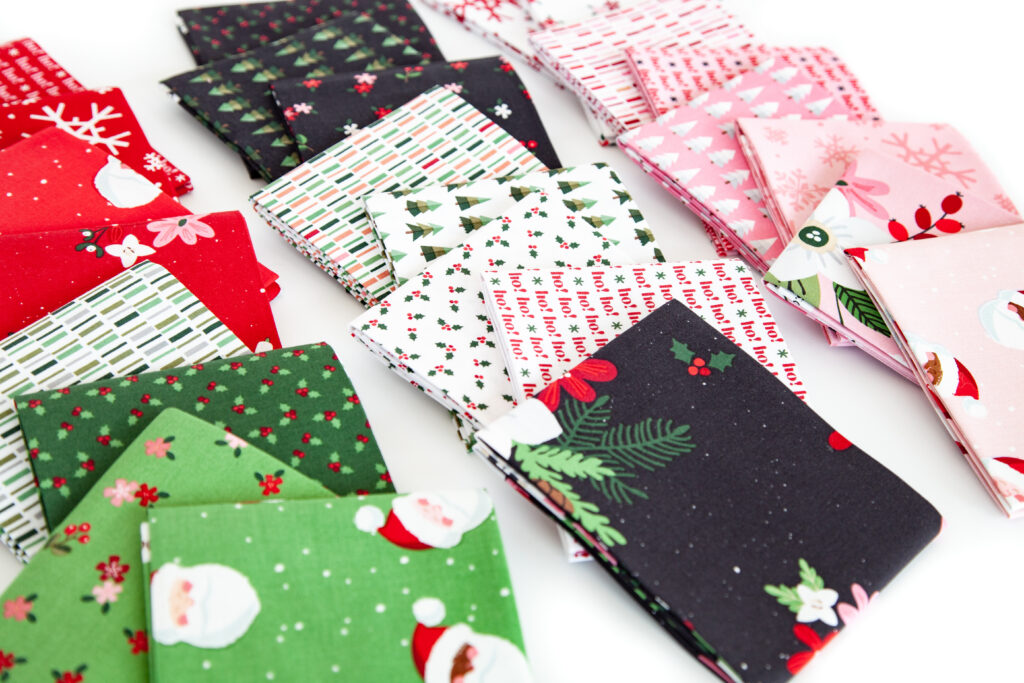 How to sew a delightful holiday mini quilt by top US sewing blog Ameroonie Designs. Image of fat quarters of Holly Holiday fabric prints.