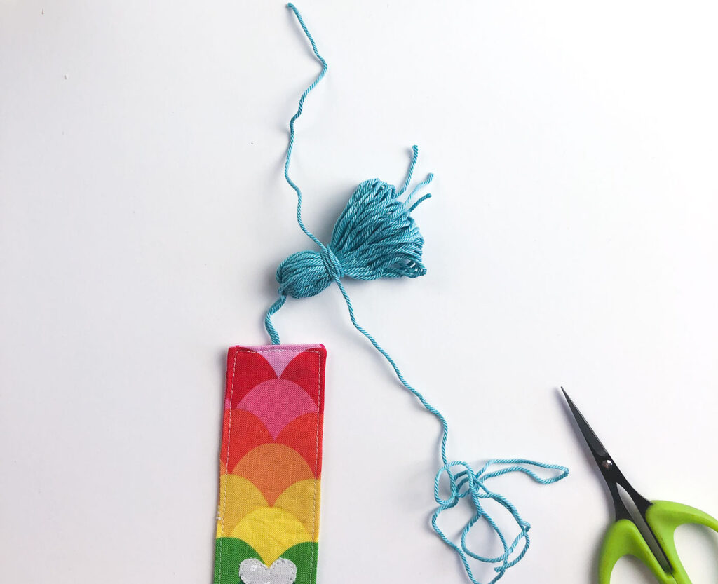 How to sew a tasseled fabric bookmark with top US sewing blog Ameroonie Designs. Image of making "neck" of tassel by wrapping with yarn.