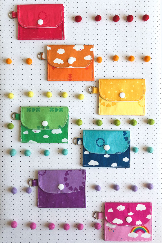 7 simple sewing projects to make this weekend from top US sewing blog Ameroonie Designs. Image of mini wallets in rainbow fabrics with felt poms.