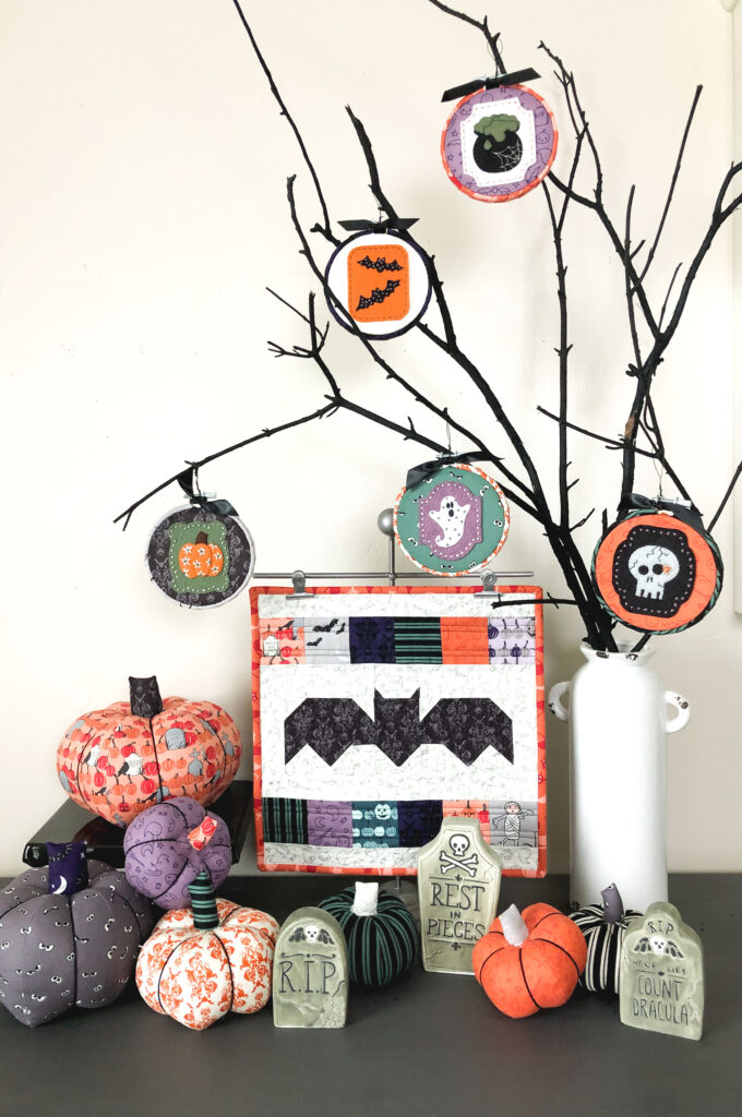 New Halloween Sewing patterns by top US sewing blog Ameroonie Designs. Image of black branches with Halloween ornaments and fabric pumpkins plus a mini bat quilt.