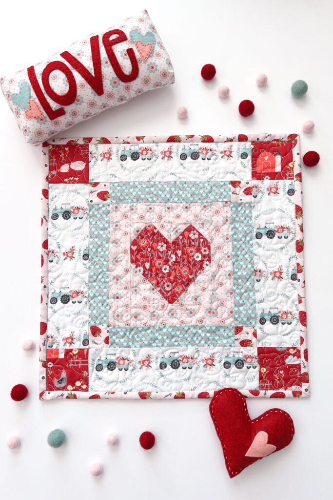 Valentine's Day decorations with top US sewing blog Ameroonie Designs. Image of mini quilt with patchwork heart, mini pillow with felt applique and felt stuffed heart.