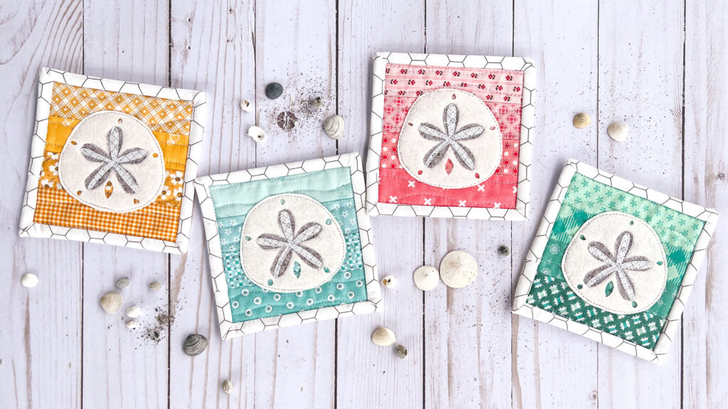 Free Sand Dollar Coaster sewing pattern by top US sewing blog Ameroonie Designs. Image of four sand dollar coaster with shells and sand.