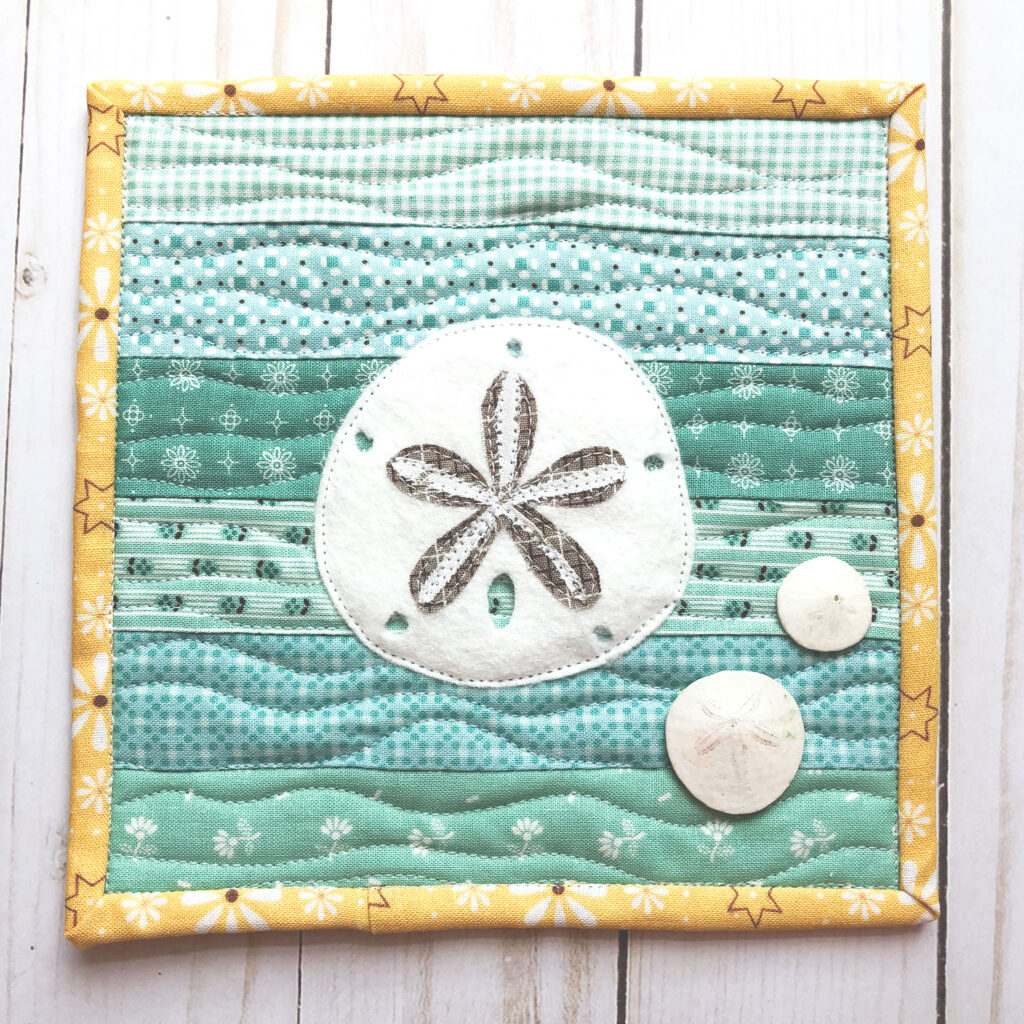 Free Sand Dollar Coaster sewing pattern by top US sewing blog Ameroonie Designs. Image of sand dollar mini quilt with sand dollar shells.