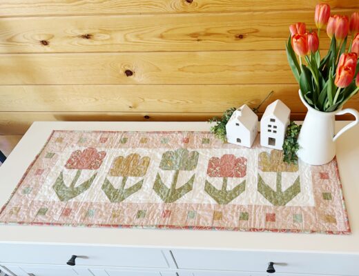 Image of quilted table runner featuring five tulips with stems and a decorative border.