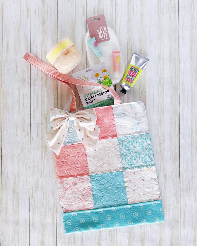 Handmade Patchwork tote displayed with spa items such as a bath mitt, lip balm, sugar scrub and lotion.